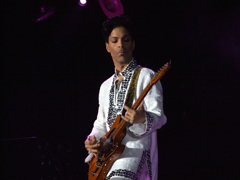 Prince playing guitar on stage.