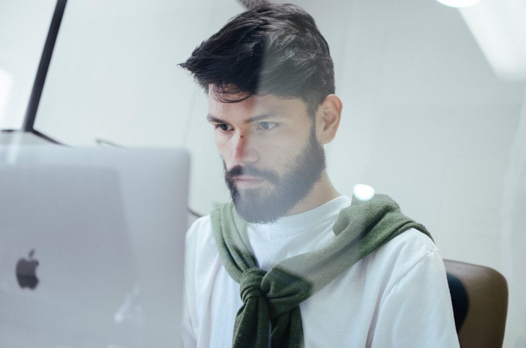 Bearded man working on a MacBook Pro.