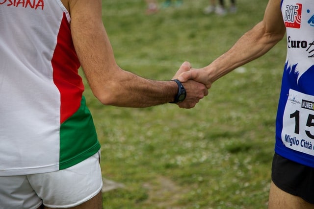 Two marathon runners shaking hands.