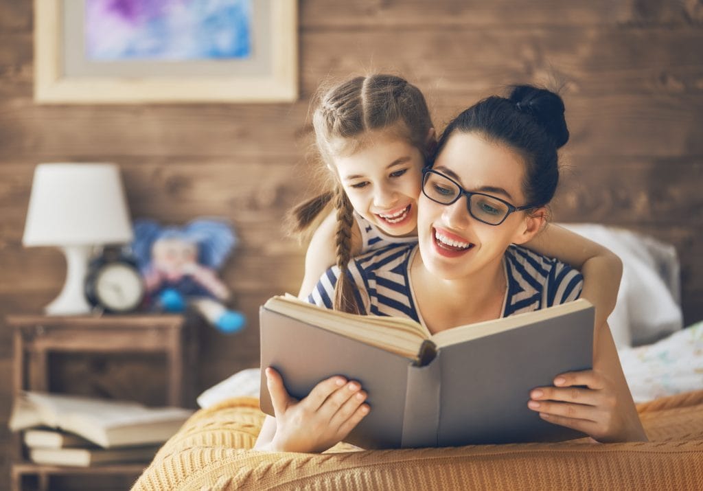 young mother reading a book to her daughter