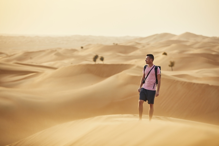Man standing on sand dune in vast desert