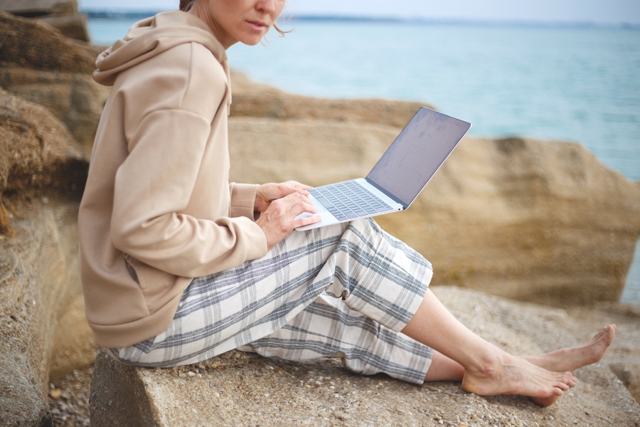 Woman with a laptop by the sea.
