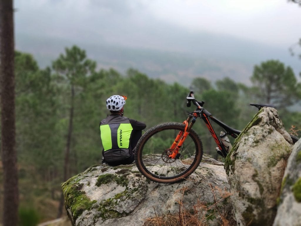 man sitting on hilltop with mountain bike