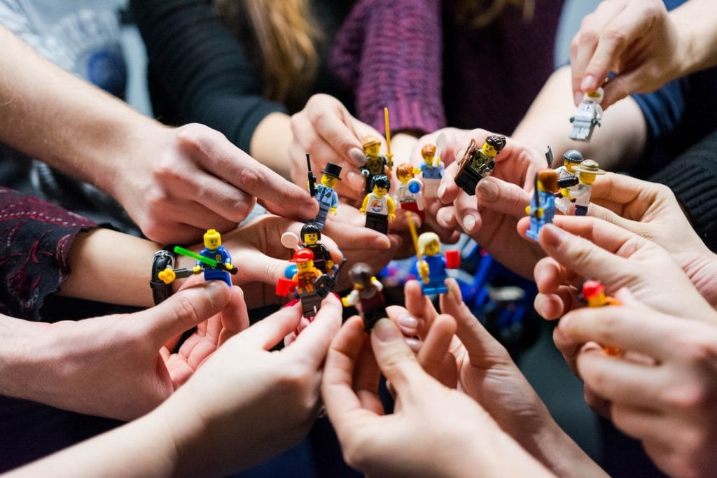 many hands holding different lego figures