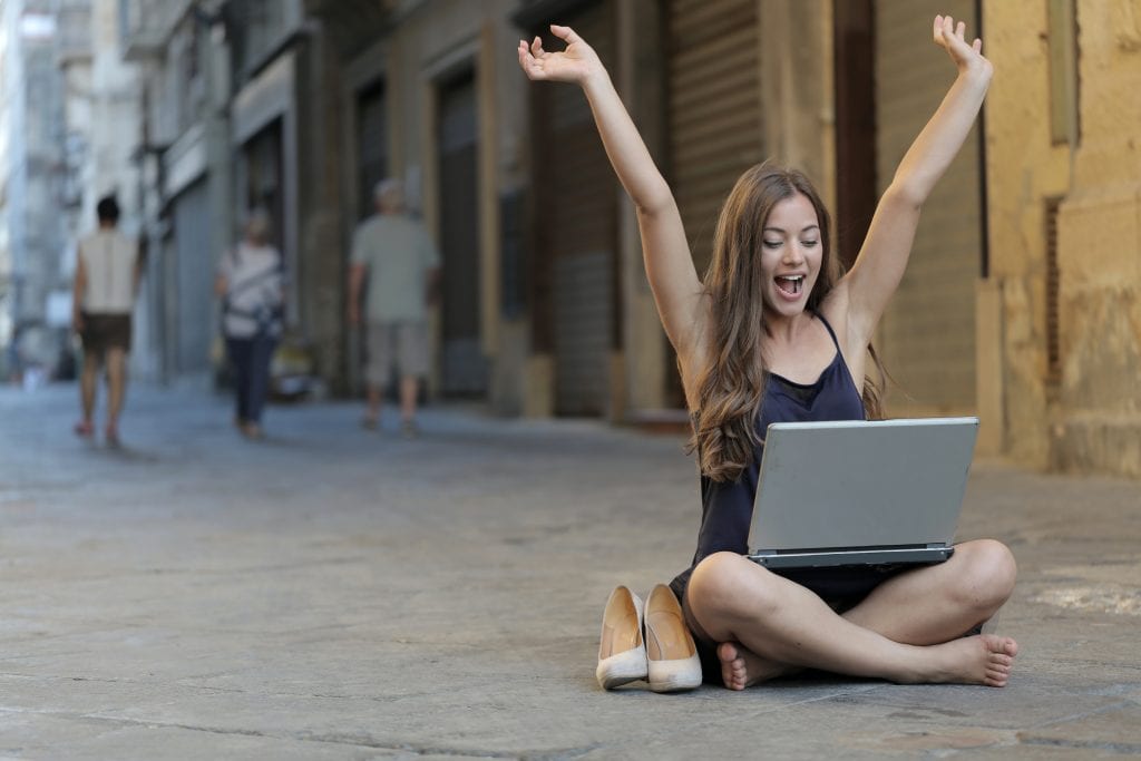 young woman working on a laptop cross legged in the middle of a street