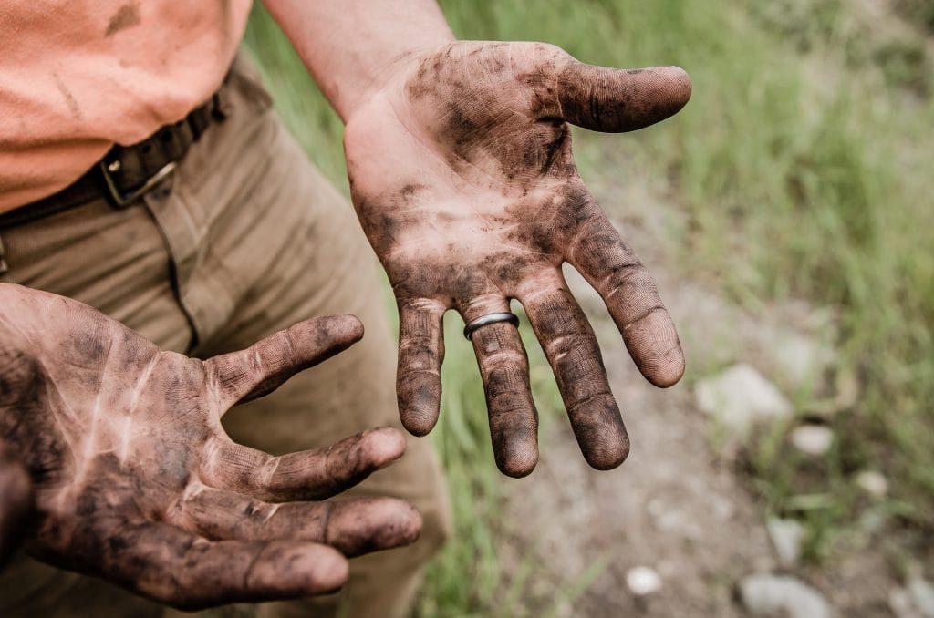 close up of man's hands with dirt on them after working