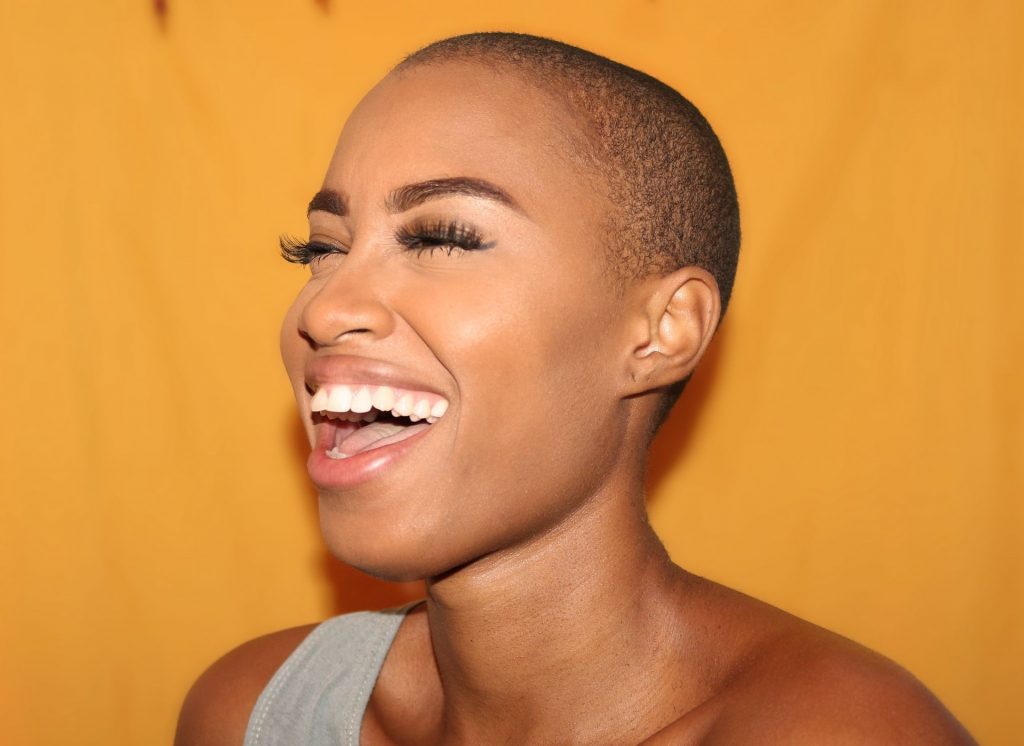 woman laughing against an orange/yellow background