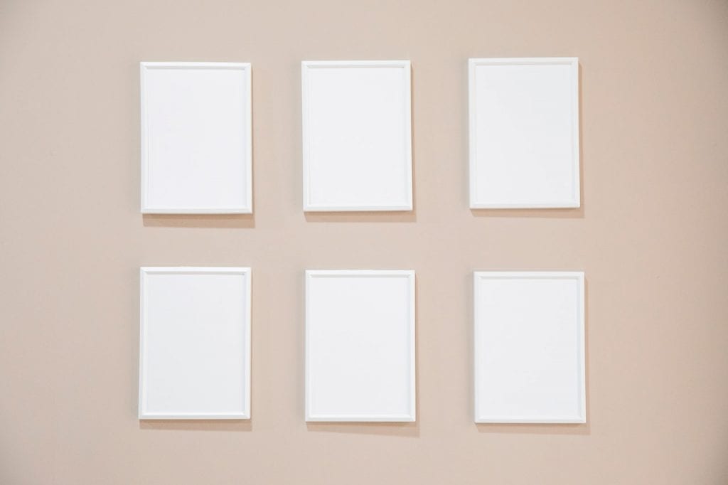 six picture frames hanging perfectly symmetrical on a wall 